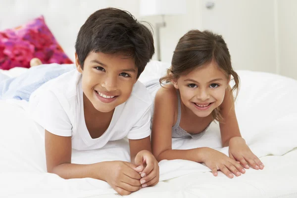 Kinderen liggend op bed in pyjama's samen — Stockfoto