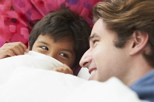 Pai e filho deitados na cama juntos — Fotografia de Stock