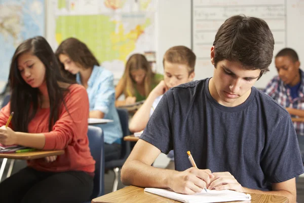 Manlig elev studerar vid skrivbord i klassrummet — Stockfoto