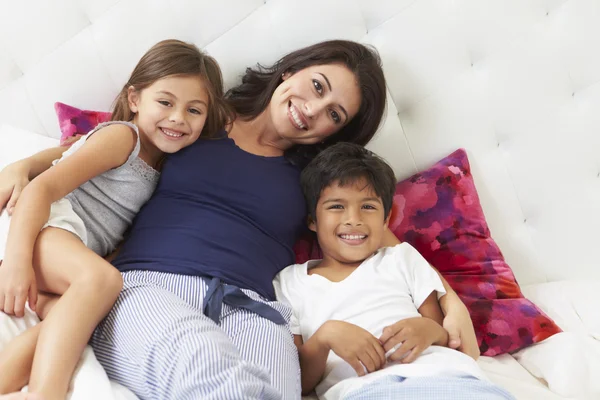 Mor och barn avkopplande i säng klädd i pyjamas — Stockfoto
