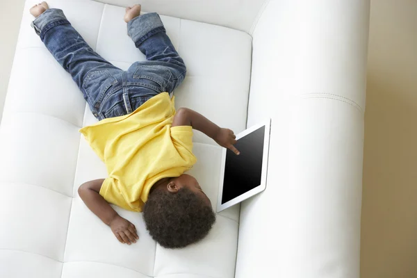 Bovenaanzicht van jongen op sofa spelen met digitale tablet — Stockfoto