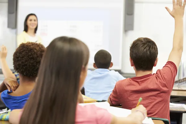 Teacher Standing In Front Of Class Asking Question Stock Photo