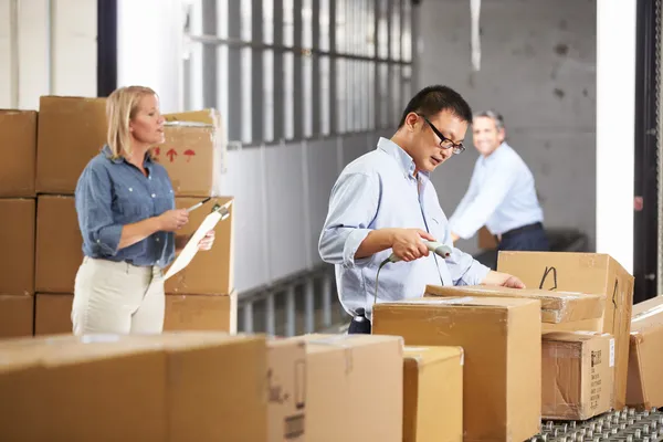 Trabalhadores que verificam bens na correia no armazém da distribuição — Fotografia de Stock