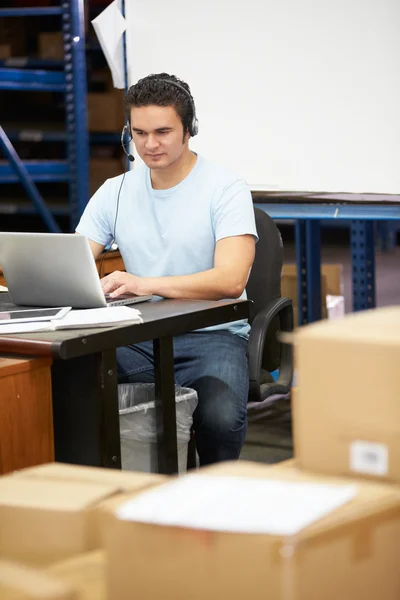 Εργαζόμενος στην αποθήκη, φορώντας ακουστικά και χρησιμοποιώντας φορητό υπολογιστή — Φωτογραφία Αρχείου