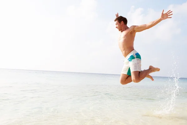 Uomo che salta in aria sulla spiaggia tropicale — Foto Stock