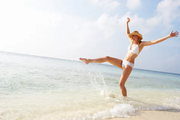 Vrouw spetteren in zee op strandvakantie — Stockfoto