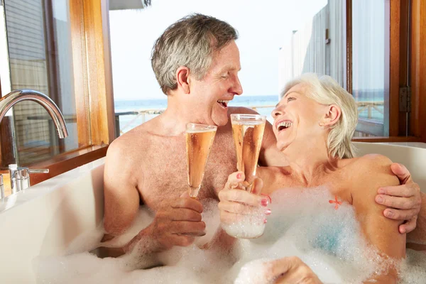 Ανώτερος ζευγάρι χαλαρώνοντας στο μπάνιο πίνοντας σαμπάνια μαζί — Φωτογραφία Αρχείου