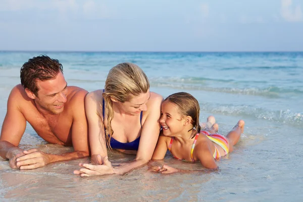 Familjen liggande i havet på tropical beach holiday — Stockfoto