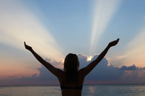 Silhouet van vrouw met uitgestrekte armen op strand — Stockfoto