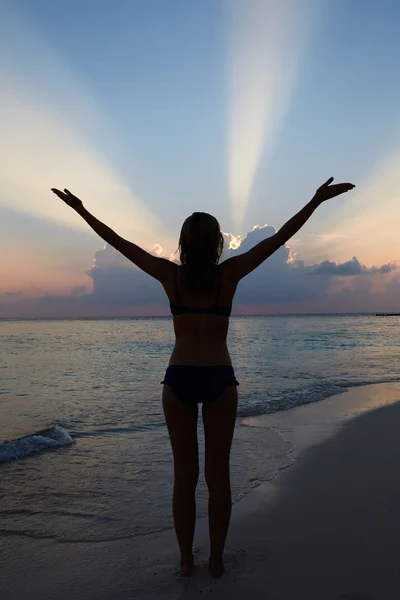 Silhouet van vrouw met uitgestrekte armen op strand — Stockfoto