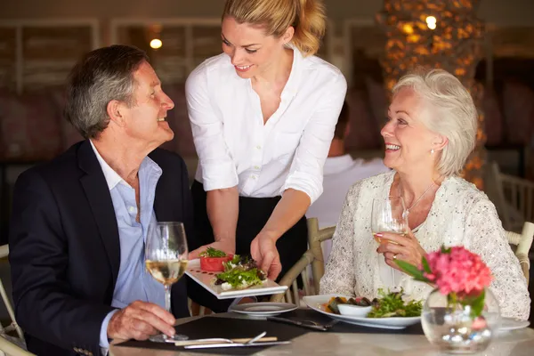 Camarera sirviendo comida a pareja mayor en restaurante — Foto de Stock