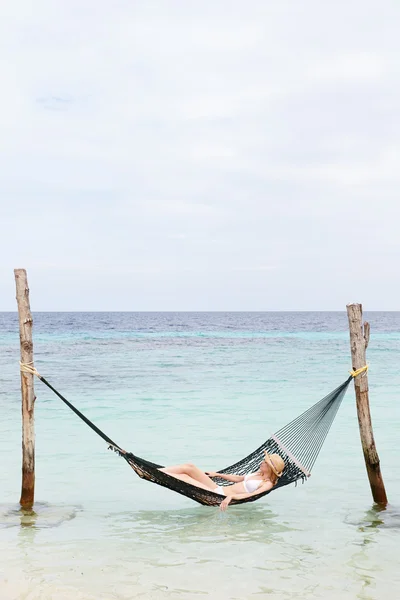 Жінка капелюсі бікіні і сонце відпочити в гамаку на пляжі — стокове фото