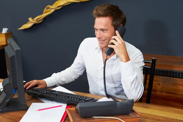 Hotel Receptionist Using Computer And Phone — Stock Photo, Image
