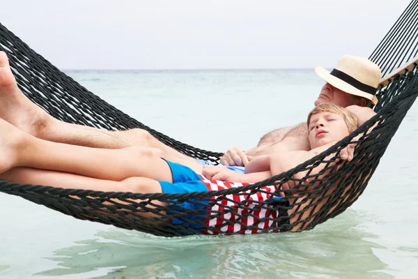 Avô e neto relaxando na rede de praia — Fotografia de Stock