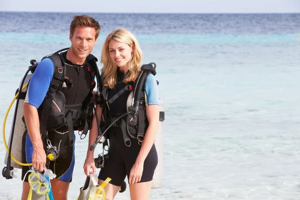 Casal com equipamento de mergulho desfrutando de férias na praia — Fotografia de Stock