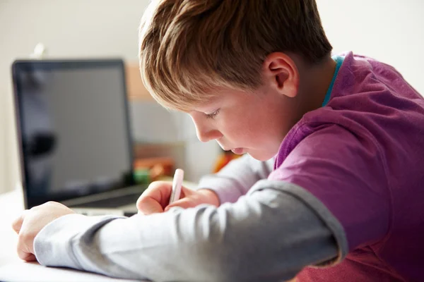 Мальчик учится в спальне с ноутбуком — стоковое фото