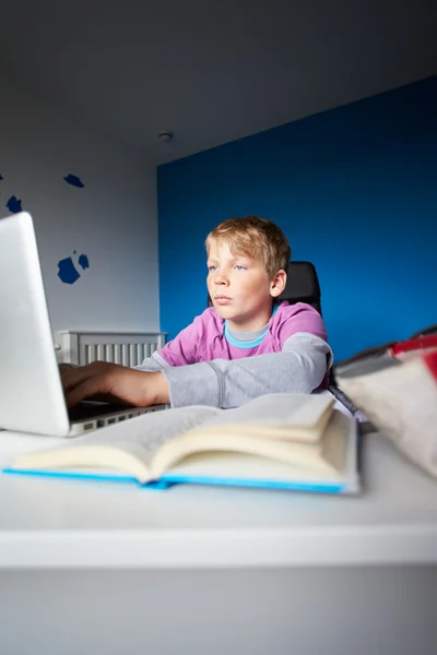 Niño estudiando en el dormitorio usando el ordenador portátil — Foto de Stock