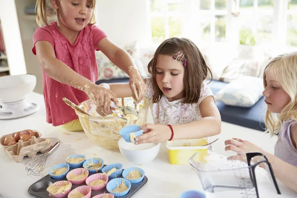 Drie meisjes maken cupcakes in keuken — Stockfoto