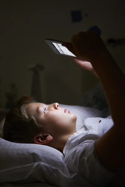 Niño mirando la tableta digital en la cama por la noche —  Fotos de Stock