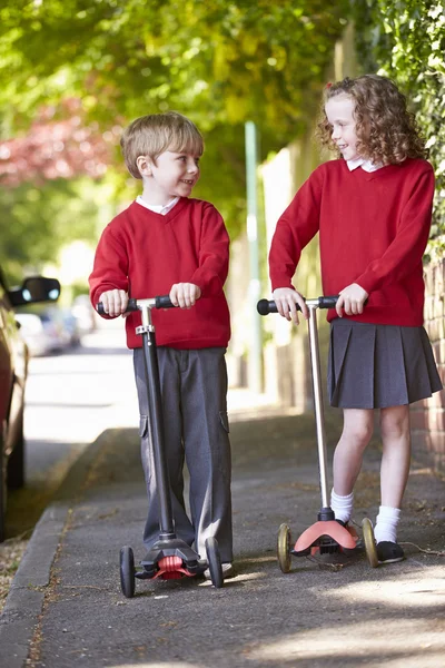 Pojke och flicka ridning scooter — Stockfoto