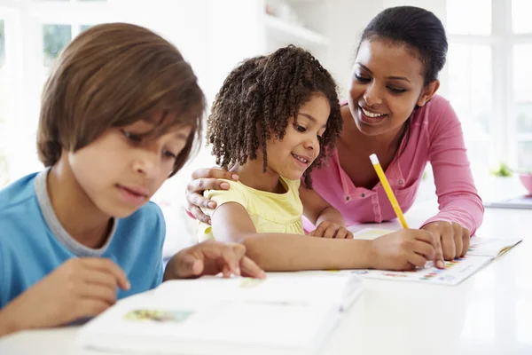 Moeder helpt kinderen met huiswerk — Stockfoto