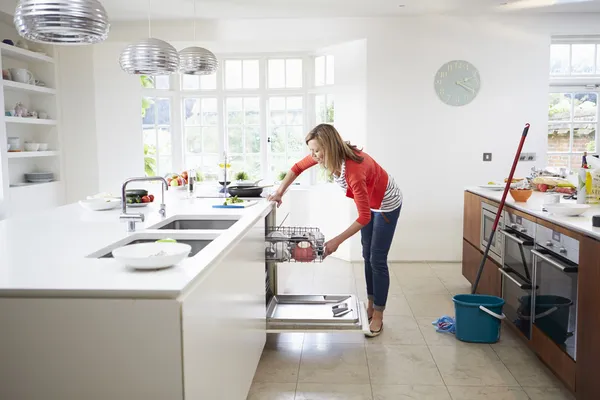 Frau lädt Teller in Spülmaschine — Stockfoto