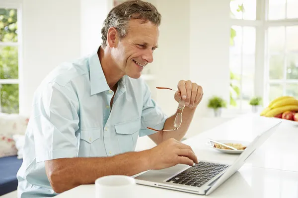 Άνθρωπος χρησιμοποιώντας φορητό υπολογιστή πάνω από το πρωινό — Φωτογραφία Αρχείου