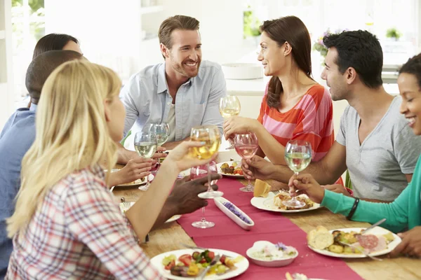 Vrienden zitten rond de tafel te eten — Stockfoto