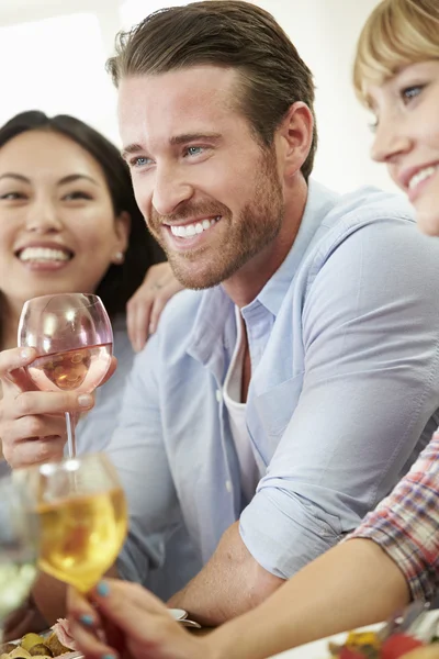 Amigos sentados alrededor de la mesa cenando — Foto de Stock