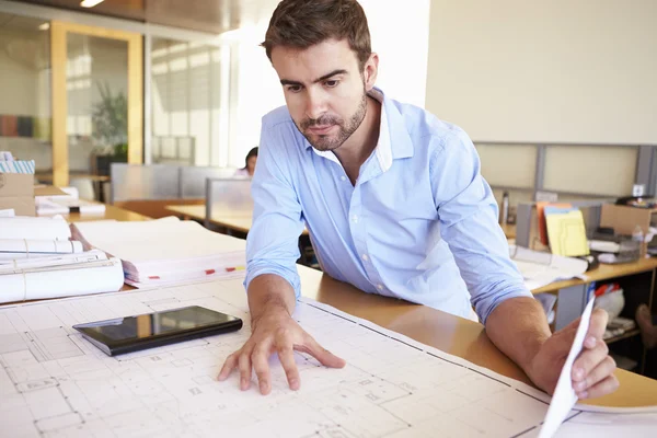 Męski architekt z cyfrowym tabletem studiuje plany w biurze — Zdjęcie stockowe