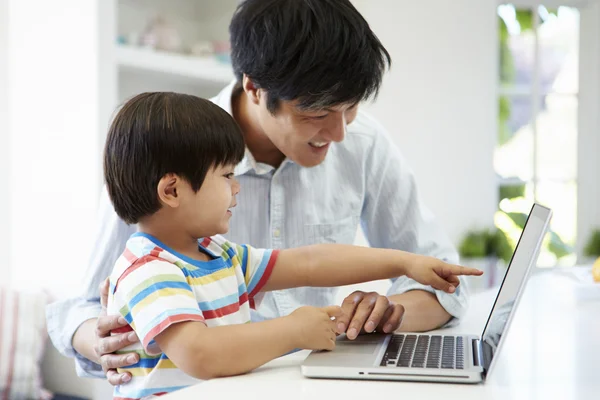 Padre ayudando a su hijo a usar el ordenador portátil — Foto de Stock