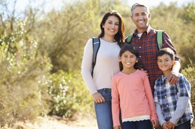Portrait Of Family Hiking In Countryside Wearing Backpacks clipart