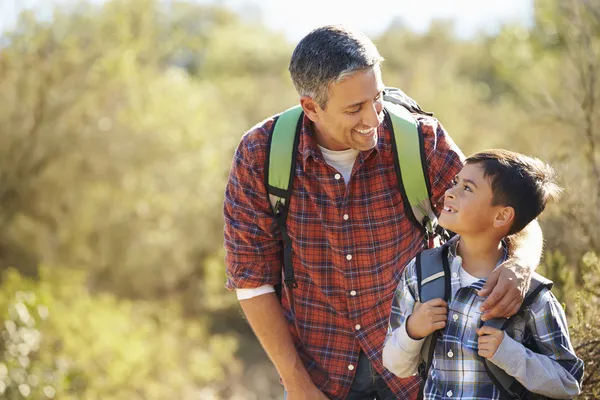 Vader en zoon wandelen in het platteland dragen van rugzakken — Stockfoto