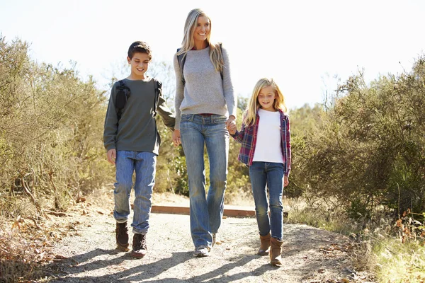 Moeder en kinderen wandelen in het platteland dragen van rugzakken — Stockfoto