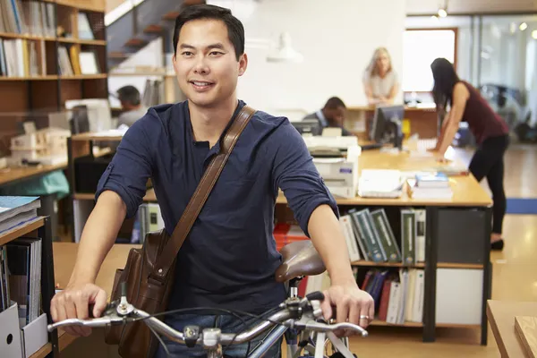 Arkitekt anländer på jobbet på cykel trycka den genom kontor — Stockfoto