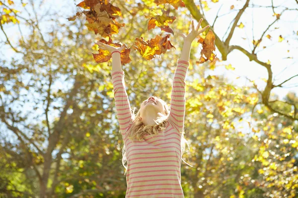 Joven chica lanzando hojas de otoño en el aire —  Fotos de Stock