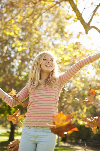 Jeune fille jetant des feuilles d'automne dans les airs — Photo