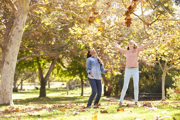 Zwei Mädchen werfen Herbstblätter in die Luft — Stockfoto