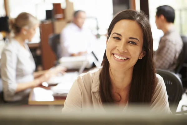 Businesswoman Working At Desk With Meeting In Background — Stock Photo, Image