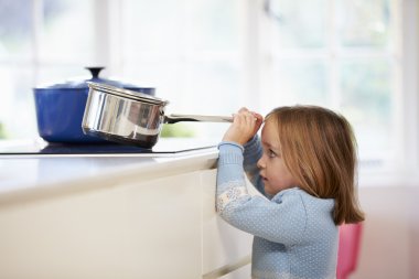 Young Girl Risking Accident With Pan In Kitchen clipart