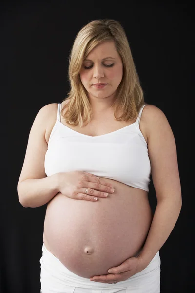 Retrato de mujer embarazada de 9 meses vestida de blanco con respaldo negro — Foto de Stock