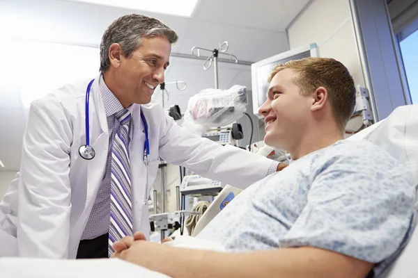 Paciente masculino joven hablando con el médico en la sala de emergencias — Foto de Stock