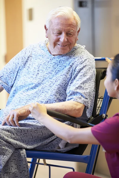 Медсестра толкает пожилого пациента в инвалидном кресле — стоковое фото