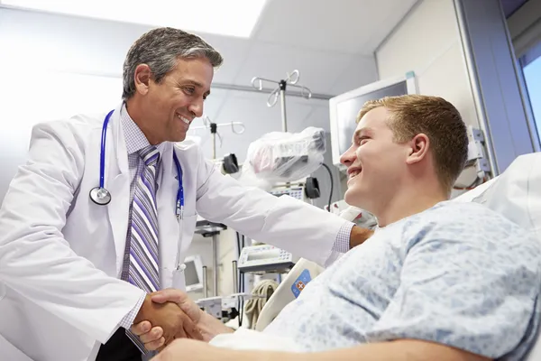 Paciente masculino joven hablando con el médico en la sala de emergencias — Foto de Stock