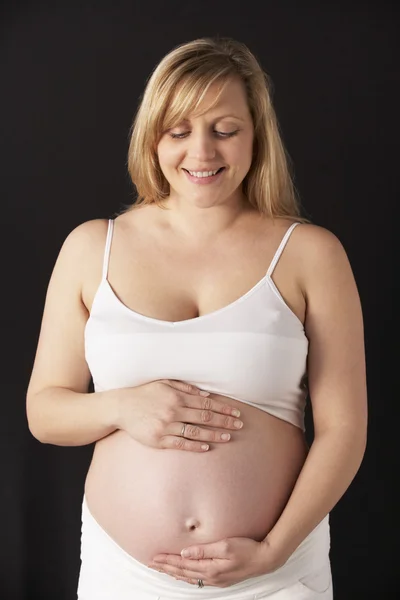 Porträt einer im 6. Monat schwangeren Frau, die weiß auf schwarzem Rücken trägt — Stockfoto