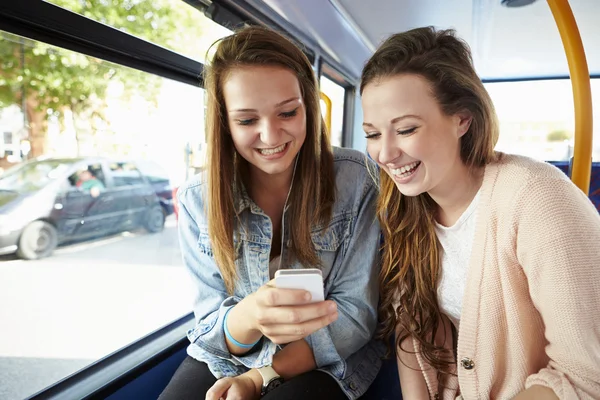 Dos mujeres jóvenes leyendo el mensaje de texto en autobús — Foto de Stock
