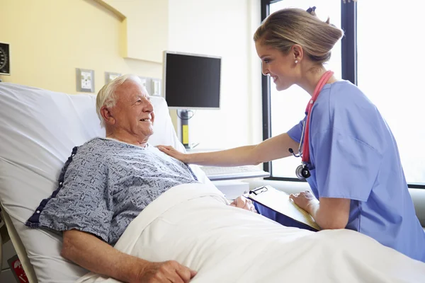 Verpleegkundige praten met senior mannelijke patiënt in een ziekenhuis kamer — Stockfoto