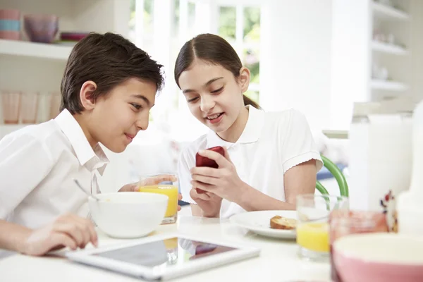 Школьники с цифровыми технологиями и мобильными за завтраком — стоковое фото