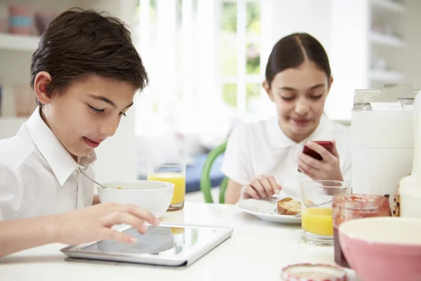 Crianças em idade escolar com tablet digital e celular no café da manhã — Fotografia de Stock