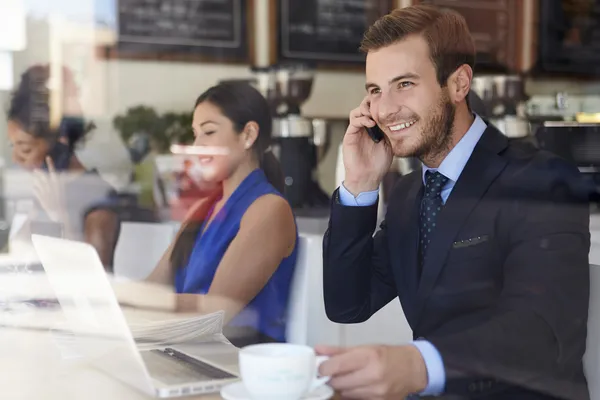 Biznesmen przy użyciu telefonu komórkowego i laptopa w kawiarni — Zdjęcie stockowe